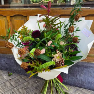 Bouquet Passionément Versus Fleurs, dahlias bordeaux et éléments séchés, devant la boutique rue Haute